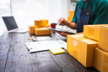 Close-up of a businessman’s hand packing items at a desk, preparing products for shipping. Highlighting delivery services for private companies online shopping with credit cards for convenience