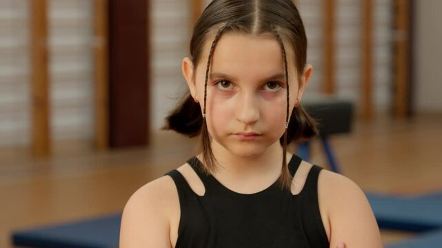 Displeased serious Caucasian little girl looking at camera child kid pupil schoolgirl gym sport angry offended school study physical education annoyed teen strong athlete workout exercise sportswoman