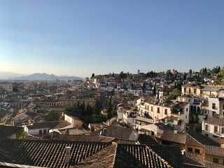 Fototapeta premium Granada, SPAIN - April 7, 2017: rooftop view of Granada landscape, filled with buildings and mountains during dusk