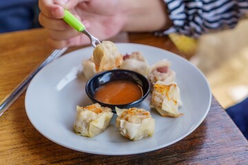 A close-up photo of a plate of dim sum, showcasing the delicate folds of wrappers and the steaming...