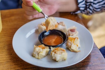 A close-up photo of a plate of dim sum, showcasing the delicate folds of wrappers and the steaming hot filling