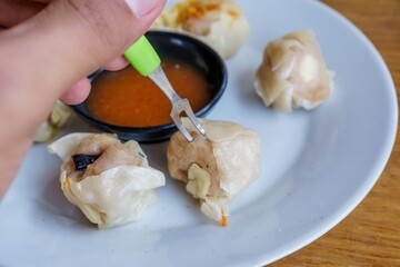A close-up photo of a plate of dim sum, showcasing the delicate folds of wrappers and the steaming hot filling