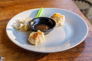 A close-up photo of a plate of dim sum, showcasing the delicate folds of wrappers and the steaming hot filling