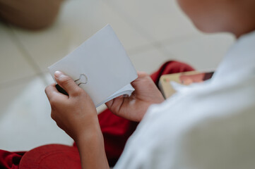 A male elementary school child is holding white paper with a cartoon picture of a person in outline form