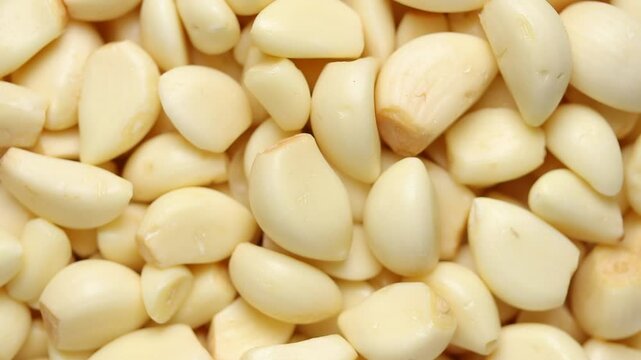 Heap of peeled garlic cloves rotating. Top view shot
