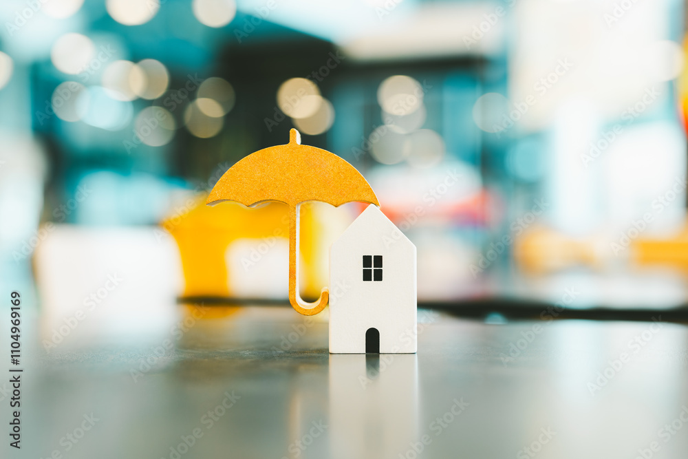 Wall mural Model of umbrella with house on wooden table concept of the system of insurance savings and Housing insurance against impending loss and fire, building fire insurance concepts.