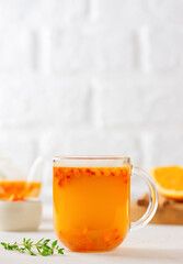 Sea buckthorn autumn tea with orange, thyme, honey and cinnamon in glass cups. Herbal vitamin tea. Vertical orientation.