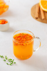 Sea buckthorn tea with orange, cinnamon, honey and thyme in glass. Herbal vitamin tea. Hot autumn drink. Vertical orientation.