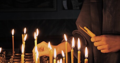 Woman lighting candles in orthodox church, symbolizing faith and devotion. Atmosphere of silence and spirituality, soft candlelight creating sacred glow during prayerful act of worship.