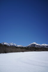 Obraz premium 雪原と雪をかぶった山と青い空