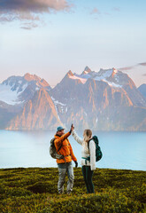 Couple man and woman traveling together hiking in Norway, friends high five hands in mountains active vacations healthy lifestyle outdoor family adventure extreme climbing tour, collaboration concept