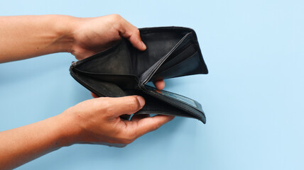 Man shows his empty wallet isolated on blue background. Bankruptcy and financial problems concept
