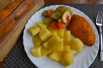 Potatoes with a piece of breaded chicken and salad.