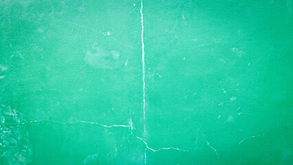 A green wall with visible cracks running vertically and horizontally, showcasing an urban decay texture