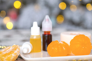 Handmade soap in the form of Orange tangerine  with bottles of dye, flavor, a block of glycerin soap base, silicone mold, on background of Christmas tree with golden light. Soap as gift new year