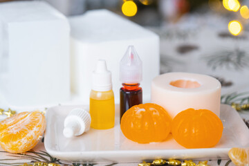 Handmade soap in the form of a tangerine with bottles of dye, flavor, a block of glycerin soap base, silicone mold, pipette. Soap as a gift, home-made