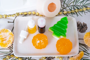 Handmade soap in the form of Orange tangerine And a green Christmas tree with bottles of dye, flavor, a block of glycerin soap base, silicone mold, pipette. Soap as a gift, home-made