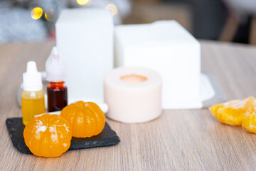 Handmade soap in the form of Orange tangerine  with bottles of dye, flavor, a block of glycerin soap base, silicone mold, on background of Christmas tree with golden light. Soap as gift new year