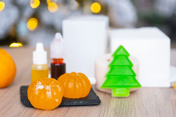 Handmade soap in the form of Orange tangerine And a green Christmas tree with bottles of dye, flavor, a block of glycerin soap base, silicone mold, pipette. Soap as a gift, home-made
