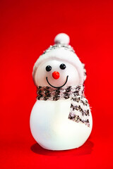 Cute little Snow man toy isolated on a red background. Christmas and New Year's decoration.