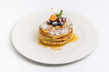 Pancakes with fruit and maple syrup on a white plate