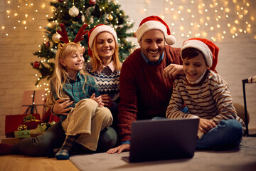 Happy family watching Christmas movie on laptop while spending holidays at home.