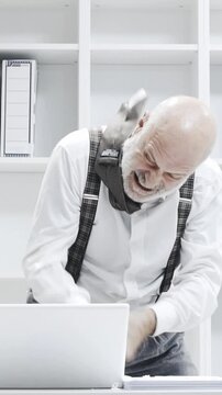 Stressed crazy businessman smashing his laptop in the office using a baseball bat, anger and computer problem concept