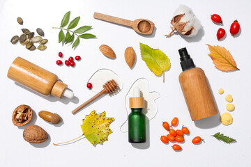 Composition with bottles of cosmetic products and different natural ingredients on light background