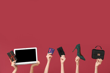 Female hands with gift boxes, laptop, credit cards and accessories on red background. Black Friday Sale