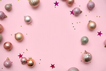 Frame made of Christmas balls and confetti on pink background