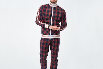 Stylish man in plaid tracksuit on plain backdrop