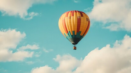 Naklejka premium A hot air balloon flying in a blue sky with white clouds.