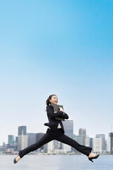 笑顔でジャンプする若いビジネスウーマン・就職活動生