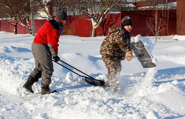 Two people are shoveling snow with a snow plow