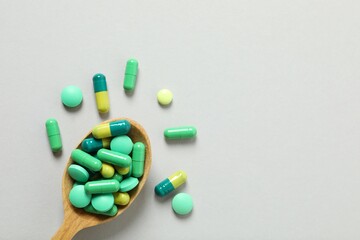 Various pills in spoon on a gray background