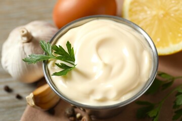 Bowl with mayonnaise and ingredients for cooking on wooden background