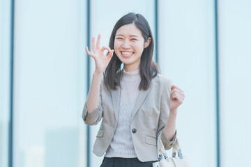 屋外で笑顔を見せるオフィスカジュアルスタイルの女性