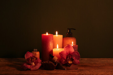 Composition with burning candles, cosmetic products and orchid flowers on dark wooden background