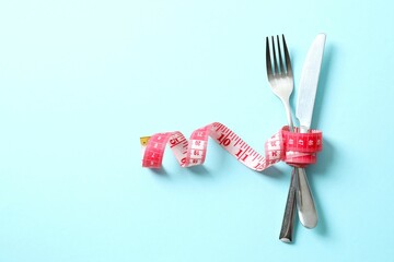 Red tape measure with cutlery on color background, top view.