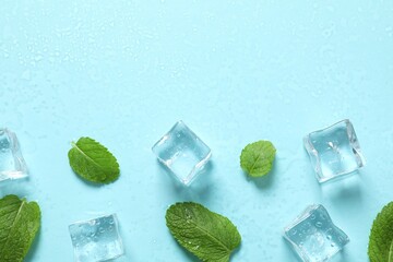 Top view photo of mint leaves, ice cubes and water drops on pastel blue background