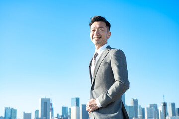 青空とビル群を背景にしたビジネスマンのポートレート