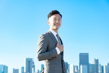 Fototapeta premium 青空とビル群を背景にしたビジネスマンのポートレート