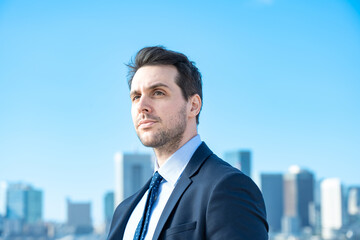 青空とビル群を背景にしたビジネスマンのポートレート