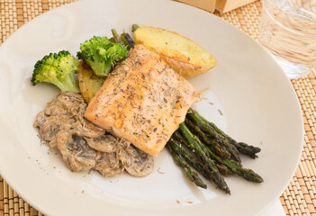 Dish of fried river trout fillet with garnish of broccoli, asparagus sprouts and mushroom sauce