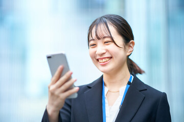 スマートフォンの画面を見るスーツ姿の若い女性