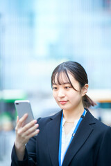 Fototapeta premium スマートフォンの画面を見るスーツ姿の若い女性