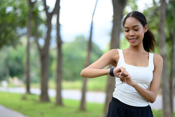 African American woman tracking her workout progress during a jog in the park