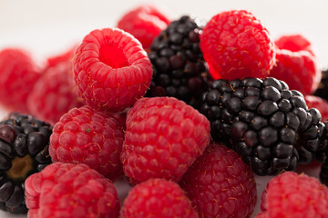 Handful of raspberry and blackberry berries on white background