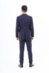 白背景の前に立つスーツ姿の男性の後ろ姿