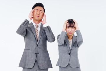 ストレスを抱えた表情をするスーツ姿の男女